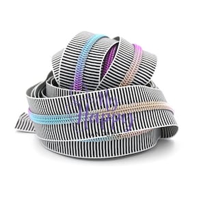 May include: Black and white striped zipper tape with iridescent rainbow colored teeth. The tape is rolled up and ready to be used for sewing projects.