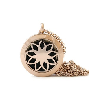 May include: A rose gold essential oil diffuser necklace with a delicate flower design. The necklace is made of stainless steel and has a chain.