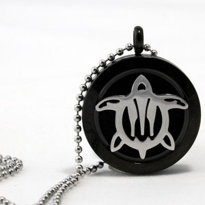May include: A black metal necklace with a round pendant featuring a silver turtle design. The pendant has a small opening on the side for adding essential oils.