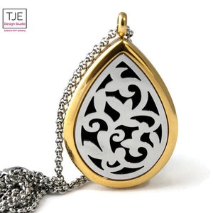 May include: A gold and silver teardrop-shaped pendant necklace with a delicate floral design. The pendant has a small opening for adding essential oils or other scents.