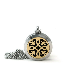 May include: A silver chain necklace with a round pendant. The pendant has a gold-colored filigree design with black cutouts.