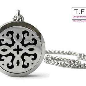 May include: A silver stainless steel essential oil diffuser necklace with a black filigree design. The necklace has a chain link style.