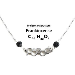 May include: A silver-colored necklace featuring a molecular structure design, with the words "Molecular Structure Frankincense" and the chemical formula C20H32O4. The necklace has two black, round beads on either side of the molecular structure.