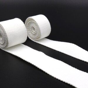 Peut inclure: Deux rouleaux de sangle en coton blanc, chacun enroulé et attaché avec une ficelle blanche. La sangle mesure environ 2,5 cm de large.