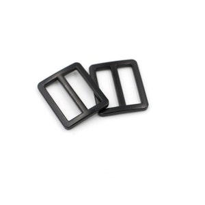 May include: Two black plastic slider buckles. The buckles are rectangular with a single slot in the center.