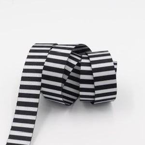 May include: Black and white striped ribbon, rolled up on a white background.