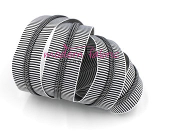 May include: Black and white striped zipper tape with a silver zipper. The tape is coiled and ready to be used for sewing projects.