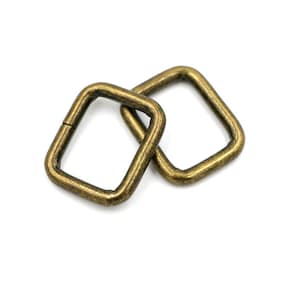 Puede incluir: Dos anillos en D cuadrados de metal de color dorado antiguo. Los anillos están entrelazados.