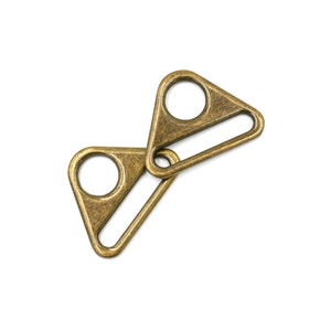 May include: Two antique gold-toned metal triangle-shaped slider buckles with a D-ring opening.