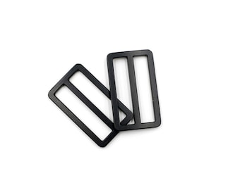 May include: Two black metal slider buckles. The buckles are rectangular with a single slot in the centre.