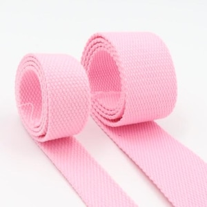 May include: Two rolls of pink cotton webbing, a type of flat woven fabric often used for straps and belts.