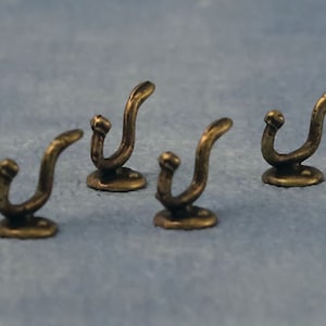 Pode incluir: Quatro ganchos de cor dourada antiga com um design de espiral decorativo. Os ganchos são montados em uma base redonda.