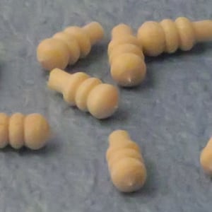 May include: A collection of 12 wooden knobs with a rounded, bulbous shape. Each knob has a series of three or four ridges, creating a textured surface. The knobs are a light, natural wood color.