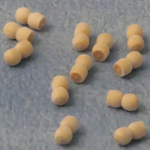 以下が含まれることがあります： 12個の木製人形の体の部品のセット。それぞれ2つの球体がつながっています。球体は薄いベージュ色で、滑らかで未加工の表面をしています。