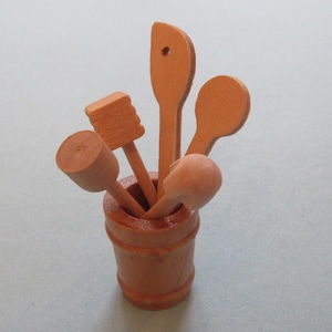 May include: A wooden utensil holder with a collection of wooden spoons, spatulas, and a wooden brush.