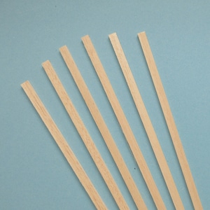 May include: Six thin, light-colored wooden strips arranged diagonally against a light blue background. The strips are rectangular and appear to be made of unfinished wood, with visible grain.