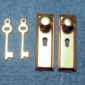 May include: Two gold-toned door knobs with a round knob and keyhole. Two gold-toned skeleton keys.
