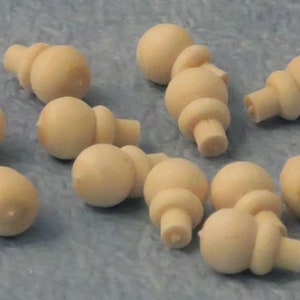 Puede incluir: Un conjunto de pequeños pomos de madera beige claro, con una parte superior redondeada y una base cilíndrica. Los pomos están dispersos sobre una superficie azul claro, mostrando su diseño simple pero funcional. Probablemente para muebles o proyectos de artesanía.