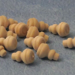 May include: A collection of 12 unfinished wooden finials, each with a unique shape and size. The finials are made of natural wood and have a smooth, sanded finish.