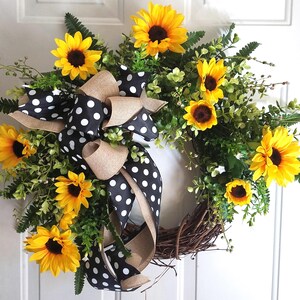 Sunflower wreath with polka dot bow hanging on white front door.