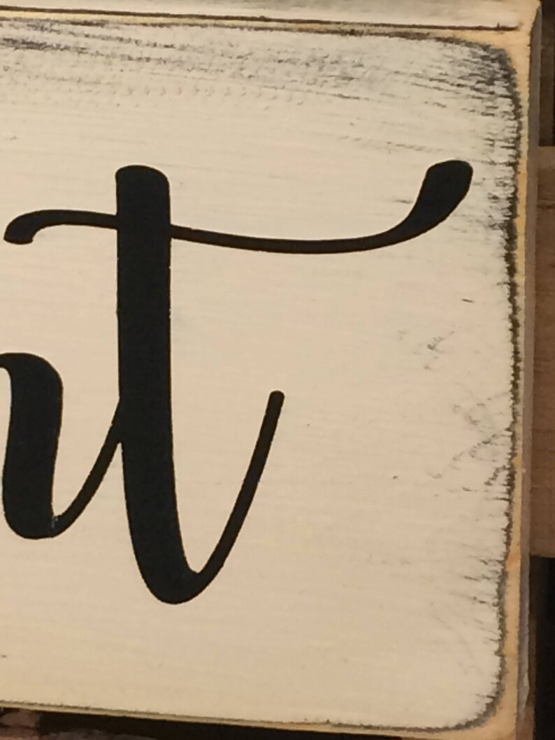 May include: A close-up of a white wooden sign with the word "sweet" in black cursive lettering. The sign has a distressed, vintage look with slightly worn edges, adding to its rustic charm.