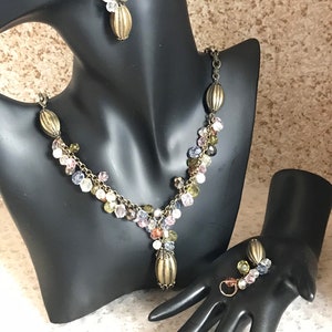 Puede incluir: Un conjunto de collar y pendientes en tono dorado con un dise&ntilde;o en cascada de cuentas de cristal multicolores.