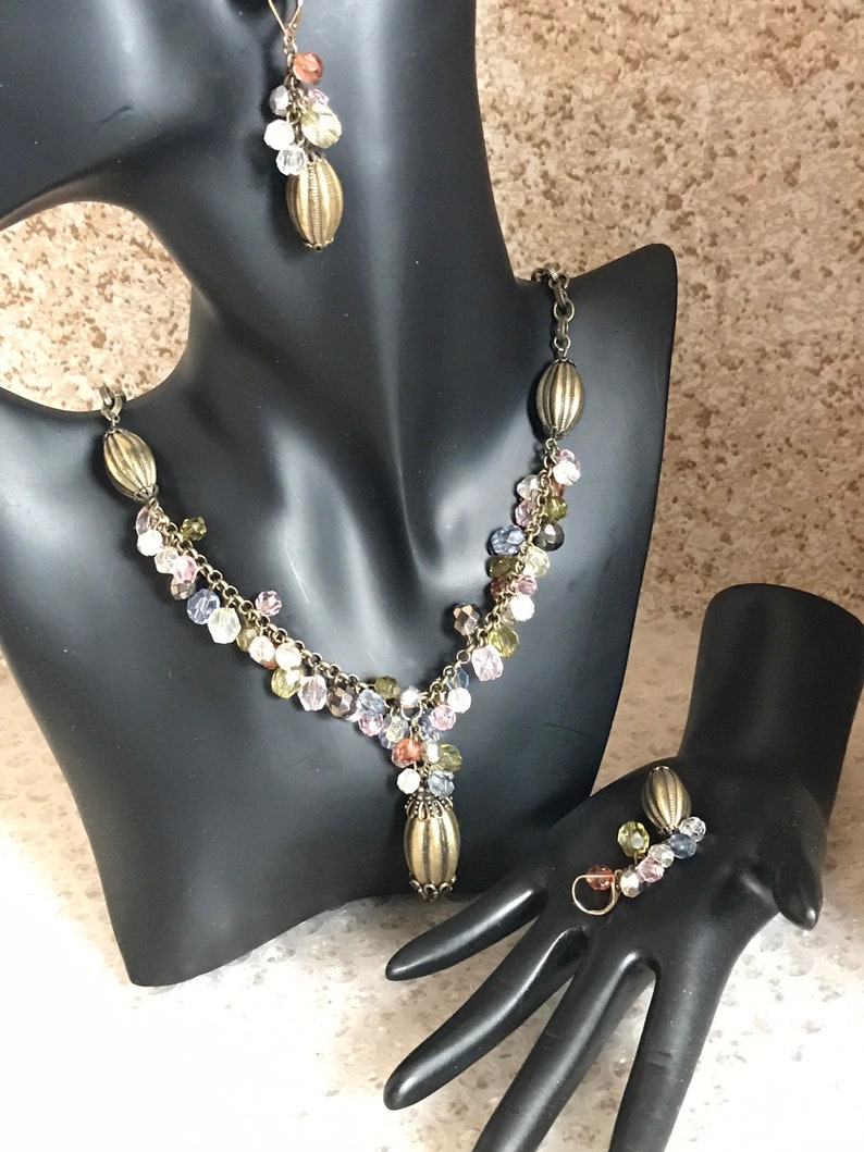 Puede incluir: Un conjunto de collar y pendientes en tono dorado con un dise&ntilde;o en cascada de cuentas de cristal multicolores.