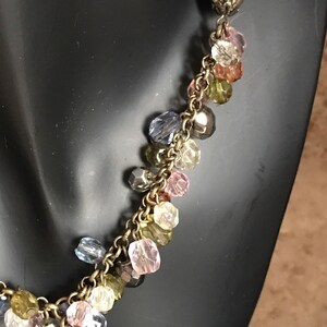 Puede incluir: Un collar de cadena dorada con una variedad de cuentas de vidrio de colores. Las cuentas son en tonos de rosa, azul, verde y marr&oacute;n.