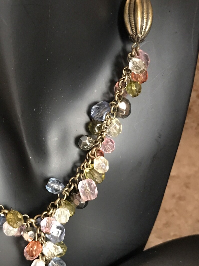 Puede incluir: Un collar de cadena dorada con una variedad de cuentas de vidrio de colores. Las cuentas son en tonos de rosa, azul, verde y marr&oacute;n.