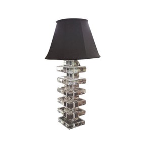 May include: A decorative table lamp with a black lampshade. The lamp base is constructed from clear, stacked, rectangular blocks. The lamp is designed to provide ambient lighting.