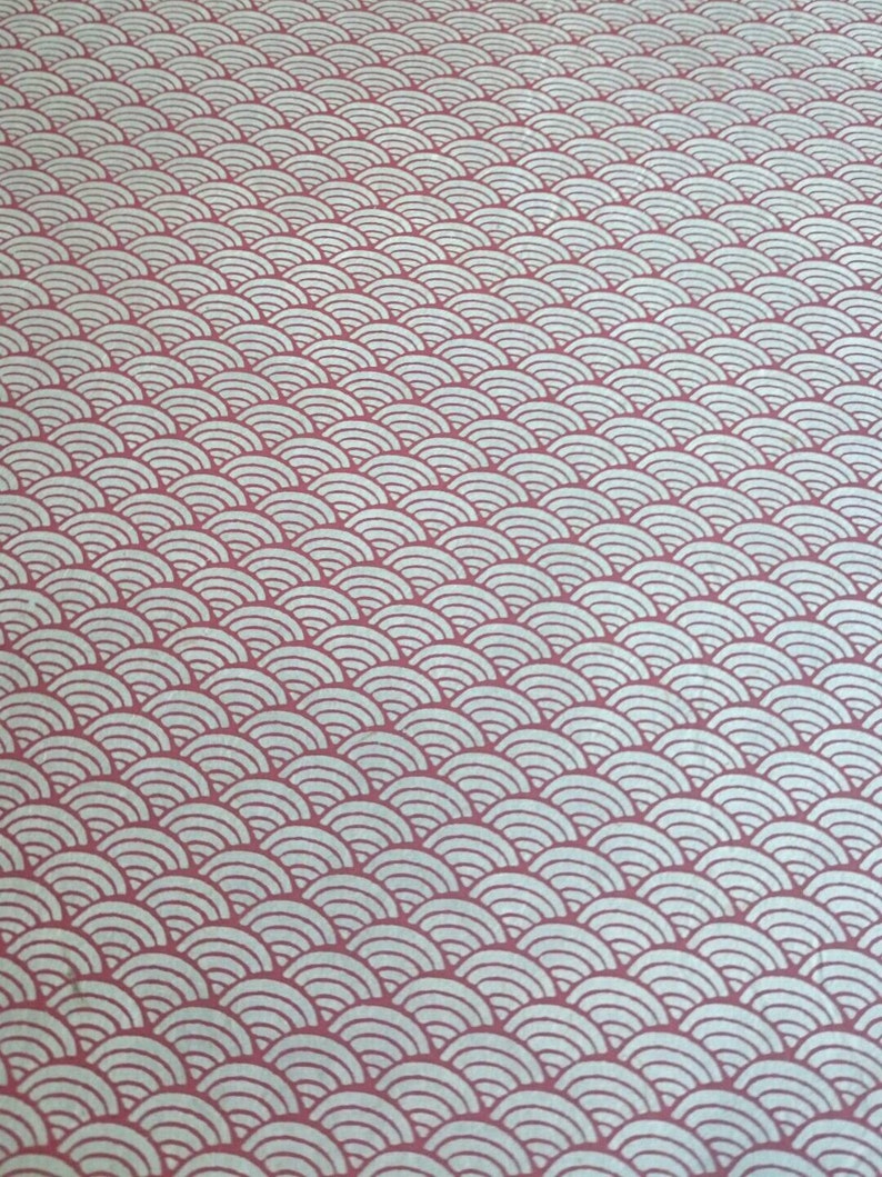 May include: A textile fabric featuring a repeating pattern of white, concentric semicircular arcs arranged in horizontal rows against a solid, muted rose-pink background. The design creates a consistent, layered wave-like visual effect across the surface.