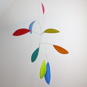 May include: A colorful mobile with seven leaves in various shades of red, blue, green, yellow, and orange. The leaves are suspended from a central point and are connected by thin wires.