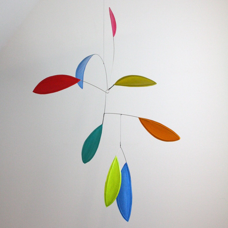 May include: A colorful mobile with seven leaves in various shades of red, blue, green, yellow, and orange. The leaves are suspended from a central point and are connected by thin wires.