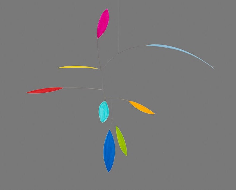 May include: A colorful mobile with seven teardrop-shaped pieces of paper in various colors, including red, yellow, blue, green, and pink. The mobile is suspended from a thin wire and hangs from the ceiling.