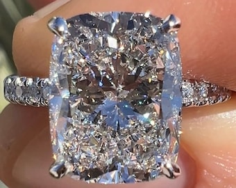 Könnte beinhalten: Ein großer, kissenförmiger Diamantring mit Pavé-Fassung. Der Ring ist aus Weißgold gefertigt und verfügt über einen funkelnden Diamanten als Mittelstück.
