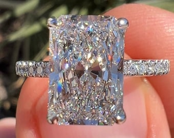 May include: A silver ring with a large, rectangular, clear diamond. The diamond has a lot of facets and sparkles in the light.