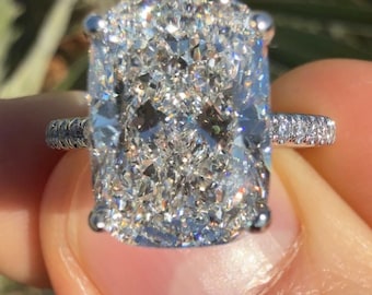 Könnte beinhalten: Ein großer, kissenförmiger Diamant-Verlobungsring in einer Weißgoldfassung. Der Diamant ist funkelnd und hat viele Facetten.