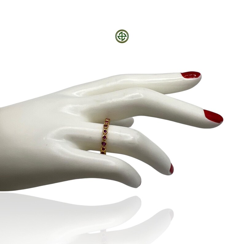 Peut inclure: Une bague en or avec une rang&eacute;e de petites pierres rondes rouges.