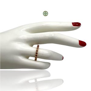 Peut inclure: Une bague en or avec une rang&eacute;e de petites pierres rondes rouges.