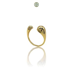 Könnte beinhalten: Ein goldener Ring mit einem einzigartigen tropfenförmigen Design. Der Ring ist an einer Seite offen und hat eine glatte, polierte Oberfläche.