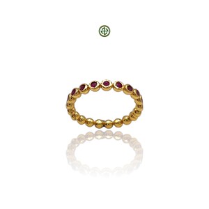 Peut inclure: Une bague en or avec une rang&eacute;e de petites pierres pr&eacute;cieuses rondes rouges.