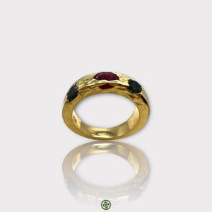 May include: Gold ring with a textured band and three gemstones: a red ruby in the center and two green emeralds on either side.