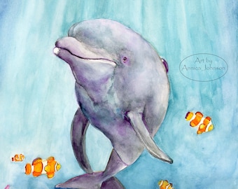 May include: A watercolour painting of a purple dolphin swimming in blue water with orange and white clownfish. The dolphin is facing the viewer and has a happy expression. The painting is signed "Art by Annika Johnson" in the top right corner.
