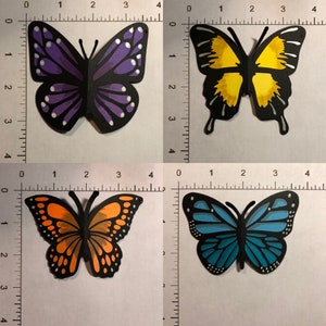 May include: Four colorful paper butterfly cutouts. One is purple with white accents, another is yellow, a third is orange, and the last is blue. Each butterfly is approximately 3 inches wide.