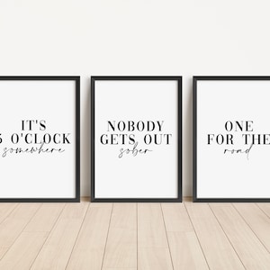 May include: Three black framed prints with white backgrounds and black text. The first print says "It's 5 o'clock somewhere". The second print says "Nobody gets out sober". The third print says "One for the road".