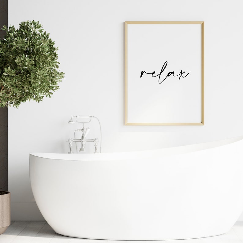 May include: A white bathtub with a silver faucet and a framed print with the word "relax" in black script.