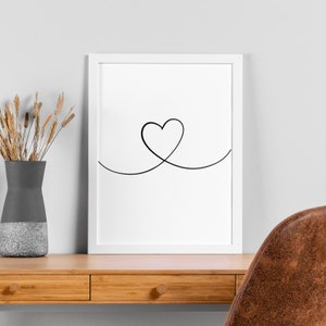 May include: A white framed print featuring a black line drawing of a heart shape created with a single continuous line.