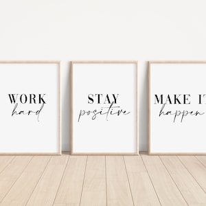 Op de afbeelding: Drie ingelijste prints met motiverende citaten. De eerste print zegt "HARD WERKEN". De tweede print zegt "POSITIEF BLIJVEN". De derde print zegt "MAAK HET GEBEUREN".