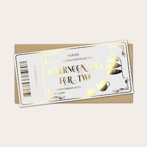 May include: A white voucher with gold foil text and illustrations for afternoon tea for two. The voucher includes the text "Afternoon Tea For Two" and "Happy Birthday XX". The voucher is on a brown envelope.