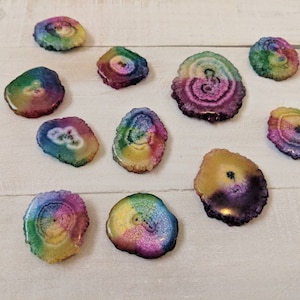 May include: Assortment of rainbow agate slices. Each slice features a unique pattern of colorful bands and swirls. The agate slices are smooth and polished, with a natural, organic look.